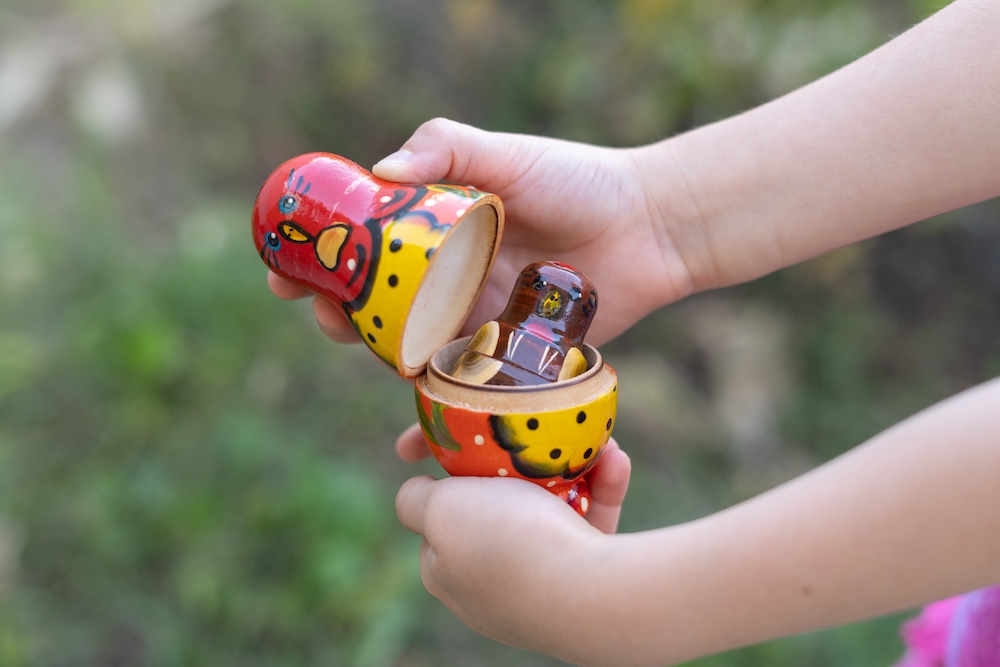 Сhild plays with matryoshka and opens it. nesting russian doll сhildren toy. matrioshka in kid's hands.
