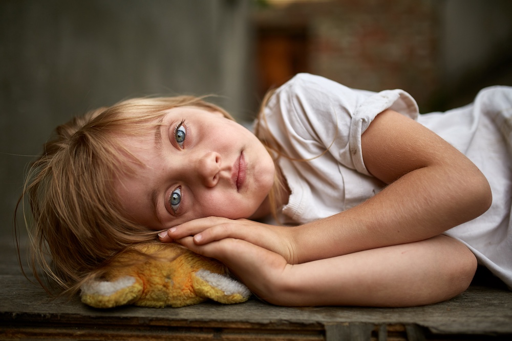 portrait of unfortunate stray kid lying on the board in the dirty alley, shallow depth of field.