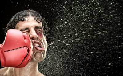 silly boxer man takes a punch in the face isolated on black.funny concept portrait.