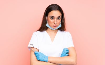 Woman dentist holding tools isolated on pink background sad