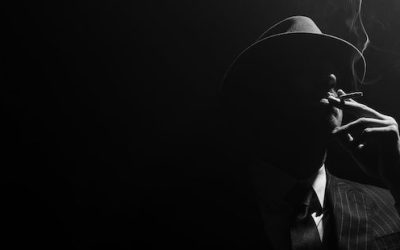Monochrome image of mafioso silhouette smoking on black background, panoramic shot