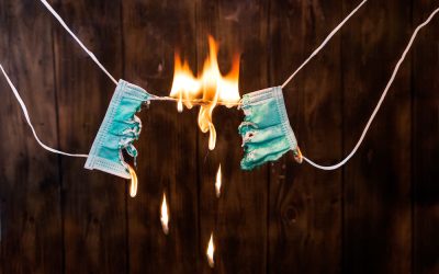 Burning a medical mask. Fake coronavirus. Coronavirus fraud and covid-19 scams or medical lies and conspiracy theory as a virus scammer spreading false medical information.