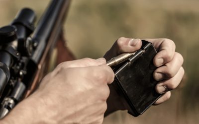 Man is charging a hunting rifle. Male hunter in ready to hunt. Closeup. Ammunition with a gun, cartridges. Hunter man. Hunting period. The man is on the hunt, sport.