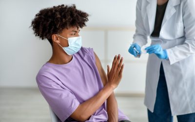 Black teenager stopping medical worker from making covid vaccine shot, being afraid of coronavirus immunization at clinic. African American adolescent scared of corona vaccination