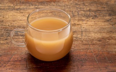 glass cup of beef bone broth on a grunge wood table